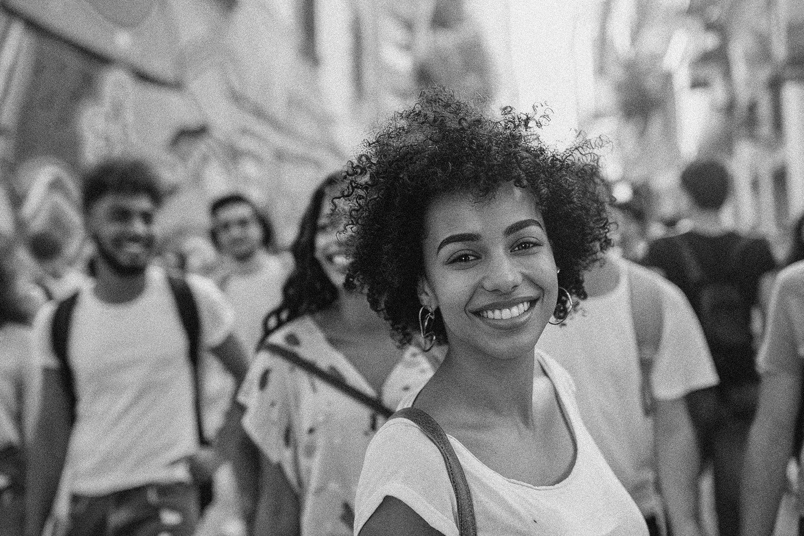 Woman smiling in a busy city street, surrounded by people